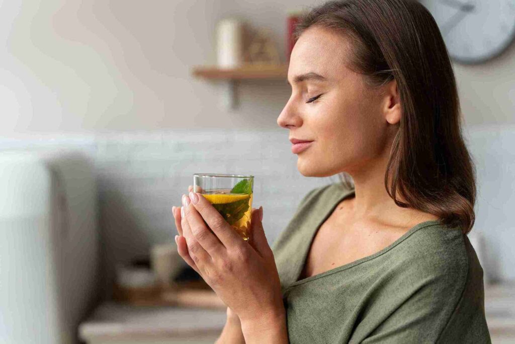 Wanita dengan kulit sehat meminum teh, menggambarkan konsep perawatan menggunakan herbal untuk kulit dari dalam