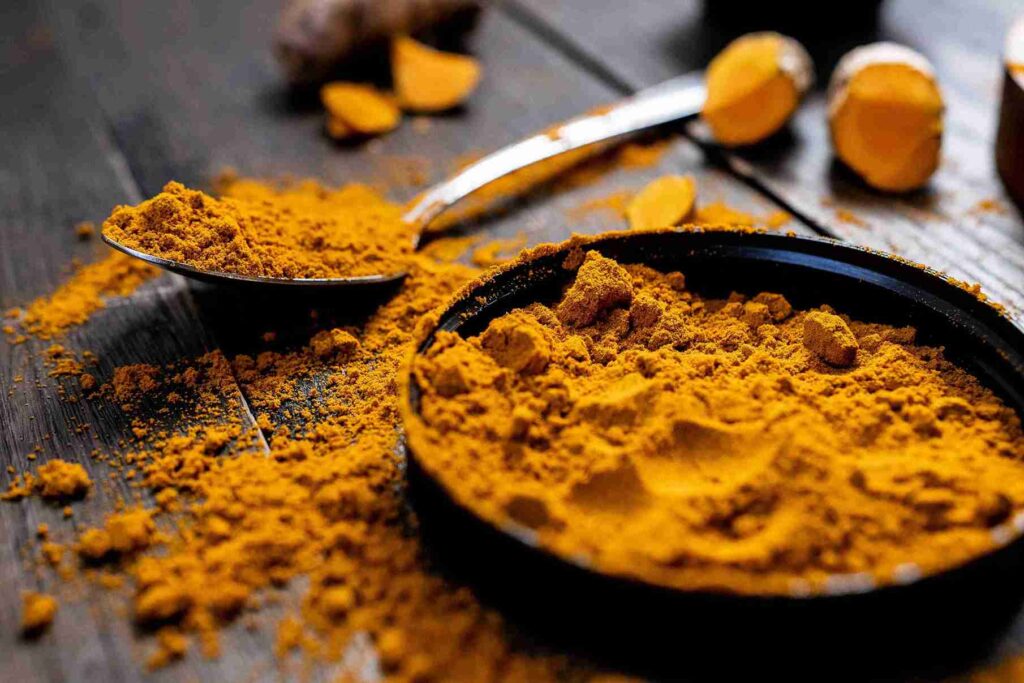 Bubuk kunyit di dalam sendok dan wadah, menunjukkan khasiat kunyit sebagai obat herbal anti-inflamasi alami