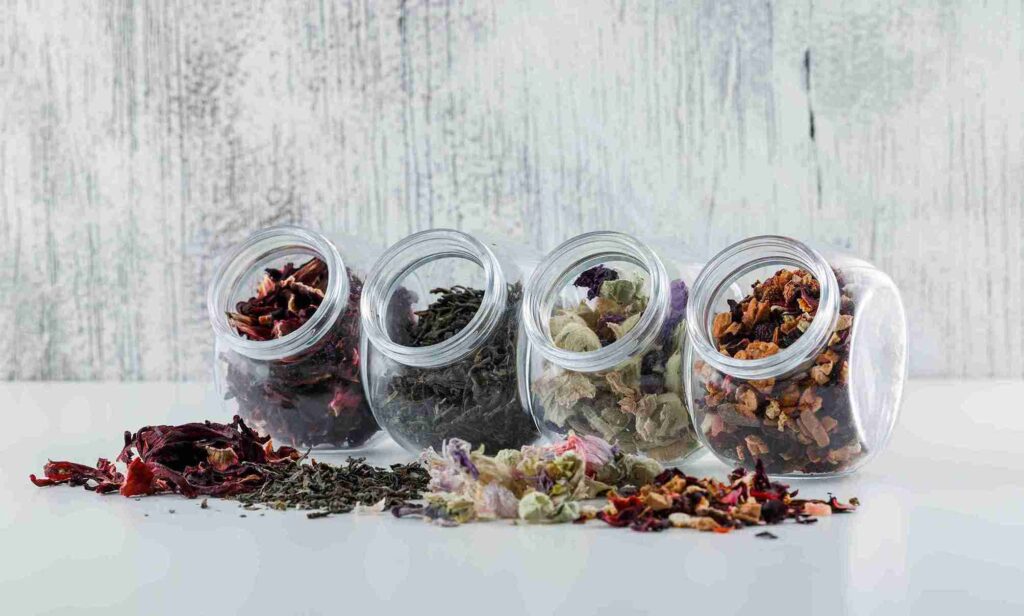 Empat toples berisi aneka rempah dan simplisia kering, menunjukkan pentingnya cara menyimpan rempah yang benar untuk setiap jenis
