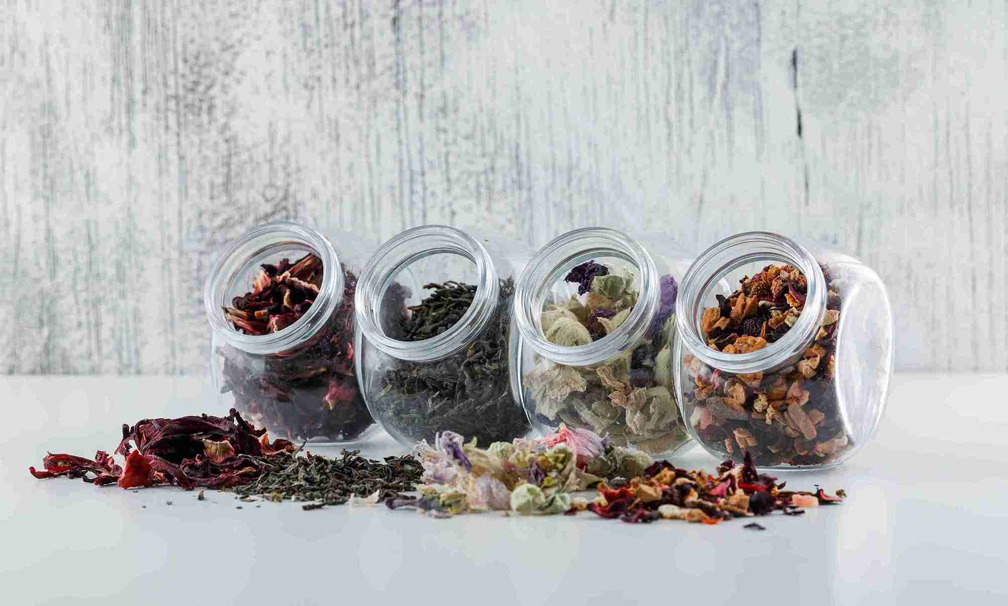 Empat toples berisi aneka rempah dan simplisia kering, menunjukkan pentingnya cara menyimpan rempah yang benar untuk setiap jenis