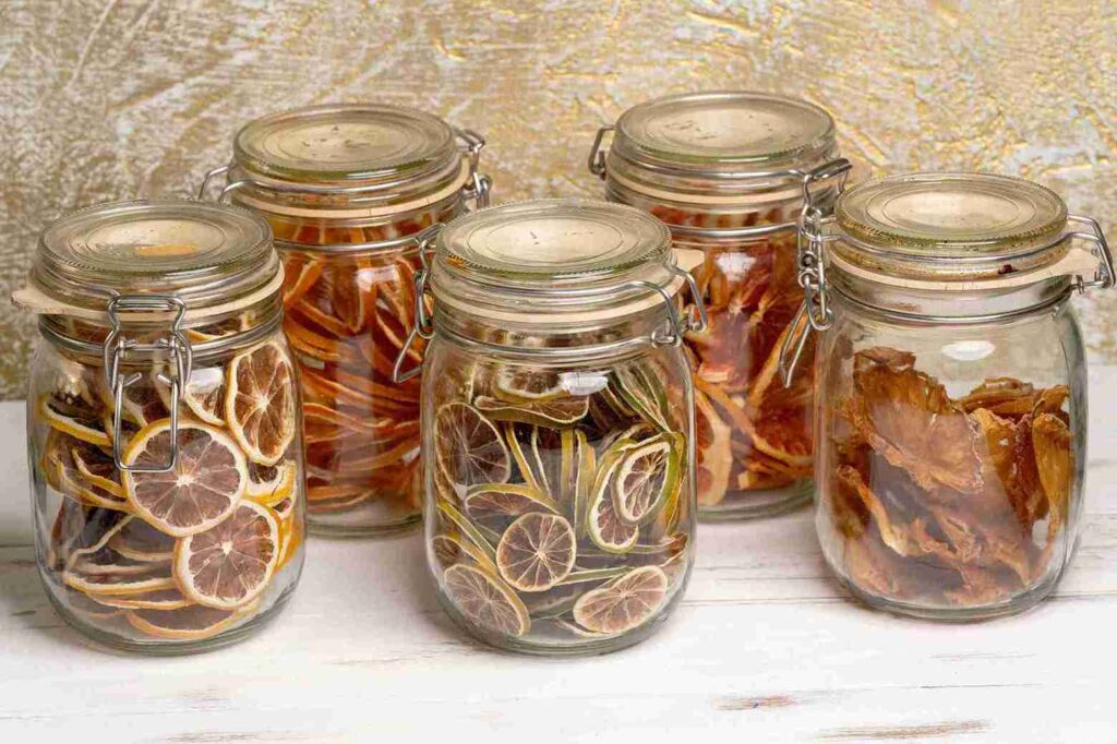 Beberapa toples berisi irisan jeruk nipis kering, menunjukkan cara praktis mendapatkan manfaat jeruk nipis untuk imunitas.