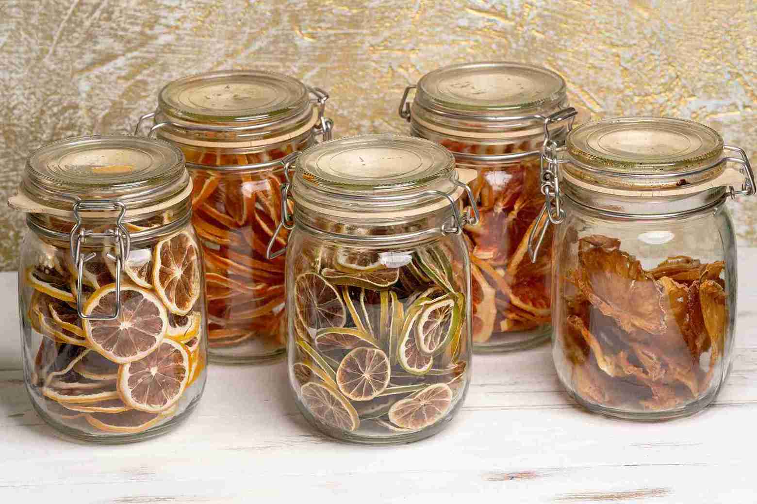 Beberapa toples berisi irisan jeruk nipis kering, menunjukkan cara praktis mendapatkan manfaat jeruk nipis untuk imunitas.
