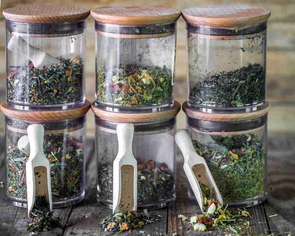 Aneka simplisia herbal dalam wadah penyimpanan bumbu di atas meja kayu