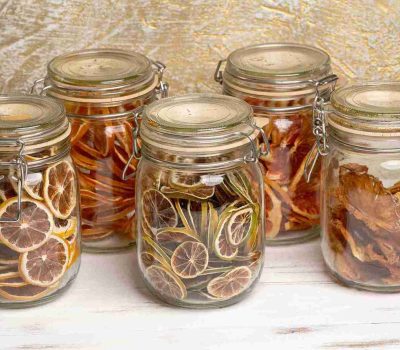 Beberapa toples berisi irisan jeruk nipis kering, menunjukkan cara praktis mendapatkan manfaat jeruk nipis untuk imunitas.